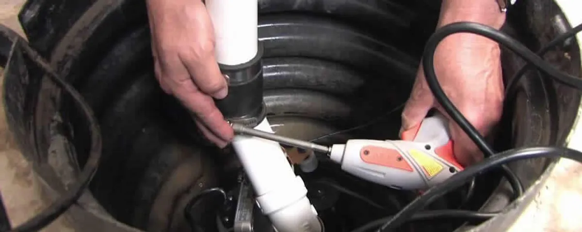 Sump pump installation technician connecting PVC discharge piping in Wilmington, NC