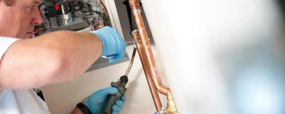 Water heater repair technician testing copper pipe connections and controls in Wilmington, NC